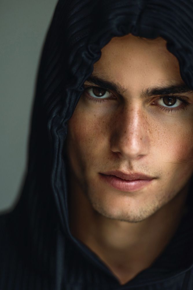 a man in a black hoodie looking at the camera with an intense look on his face