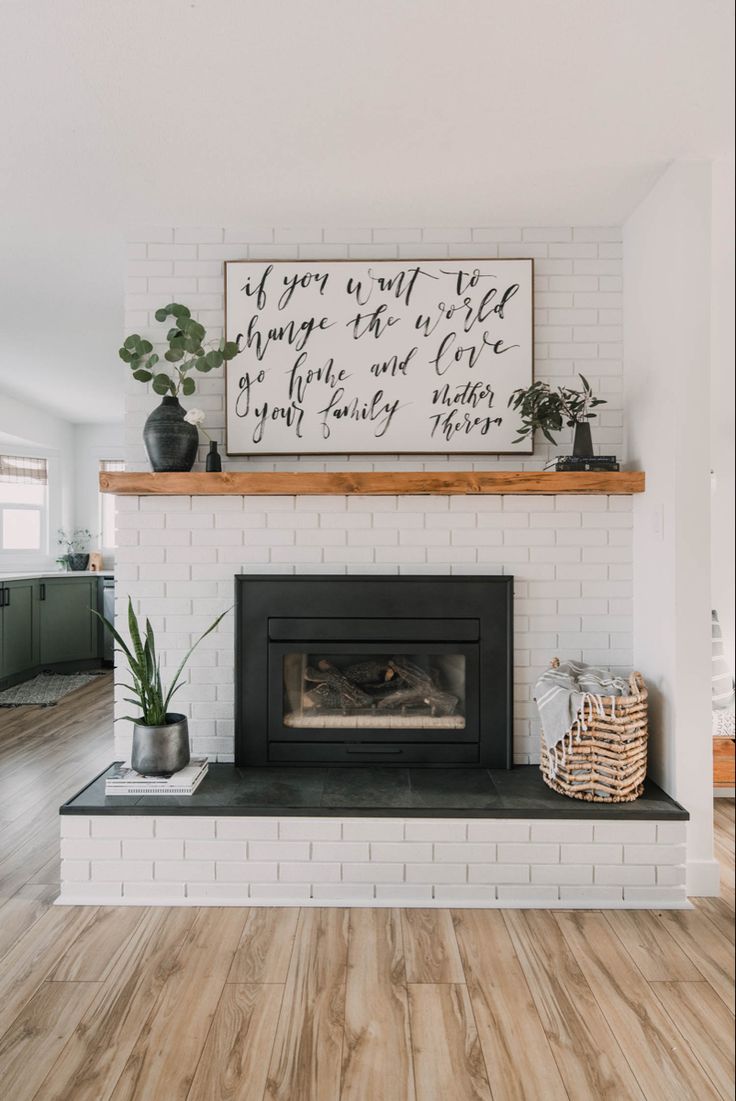 a white brick fireplace with wood floors and a sign above it