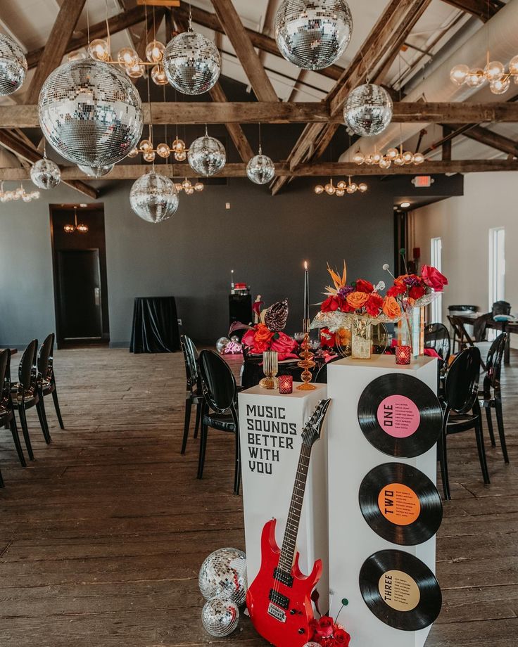 a record player and guitar are on display in the middle of a room with disco balls hanging from the ceiling