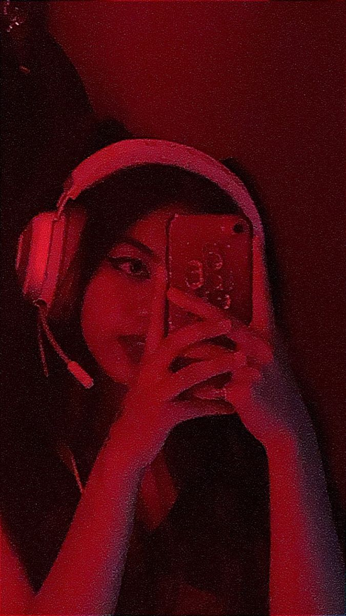 a woman wearing headphones is taking a photo with her cell phone in the dark