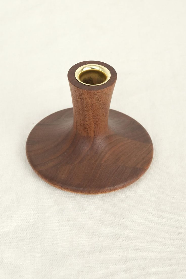 a small wooden object on a white tablecloth with a gold ring in the center