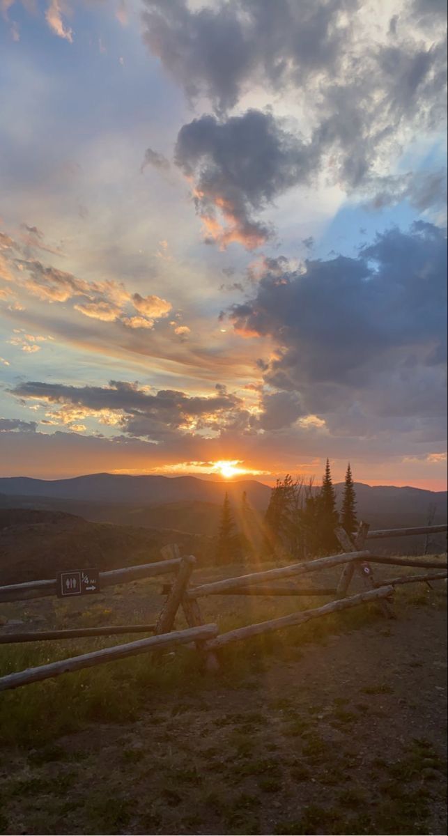 the sun is setting behind a wooden fence