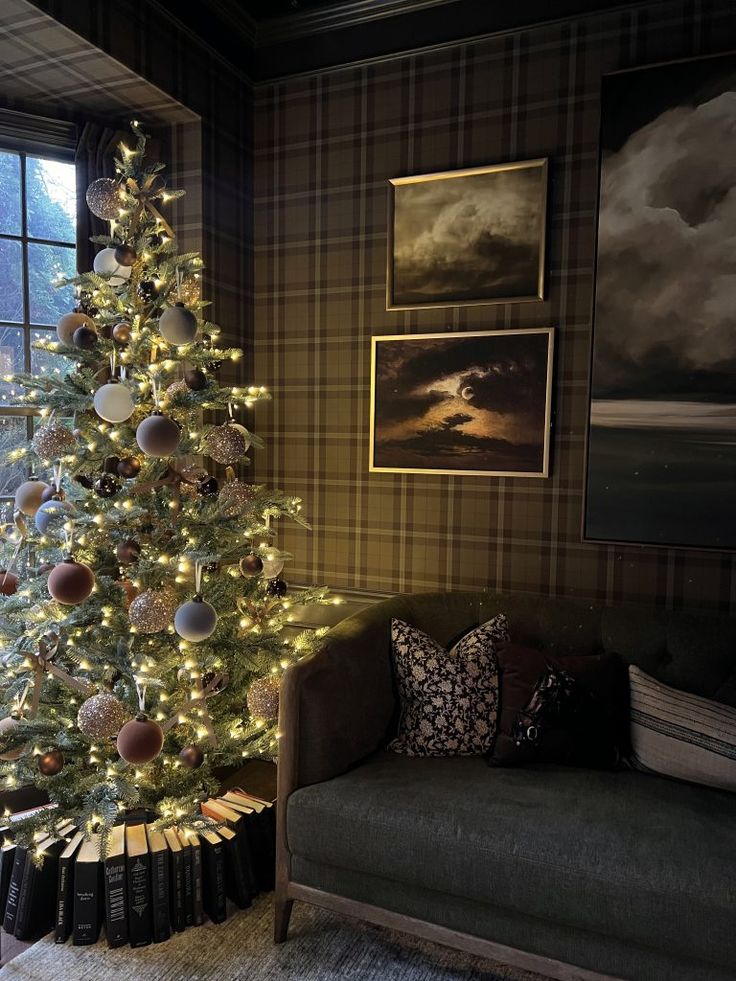 a living room with a christmas tree in the corner and pictures on the wall behind it