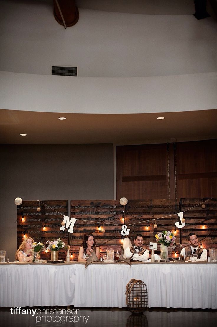 a group of people sitting at a table in front of a wall with letters on it