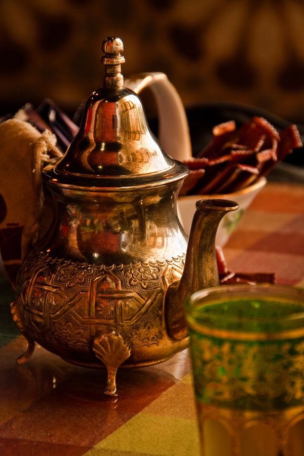 a silver teapot sitting on top of a table next to a cup and saucer