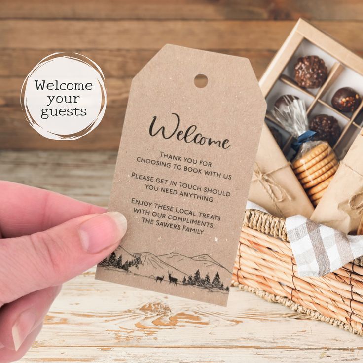 a person holding up a welcome card next to a basket with cookies and other items