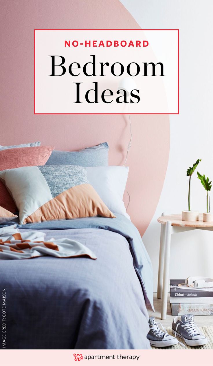 there is a bed with blue sheets and pillows on it, next to a pink wall