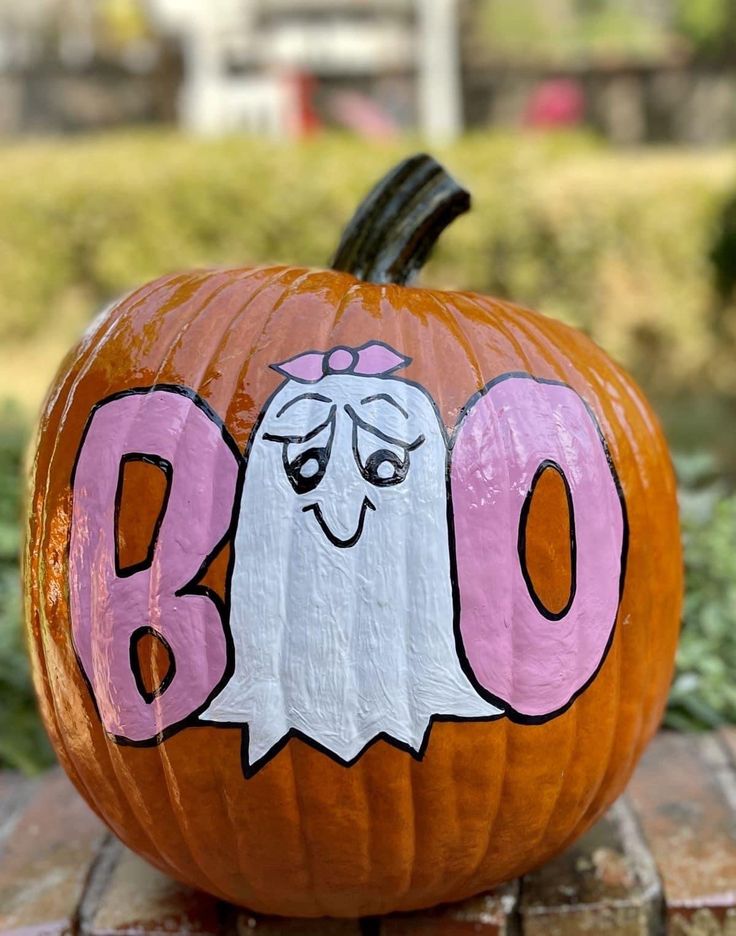 a pumpkin with the word boo painted on it and a ghost face in the center