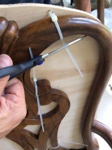 a person is cutting wood with scissors on a wooden chair that's being made into a sculpture