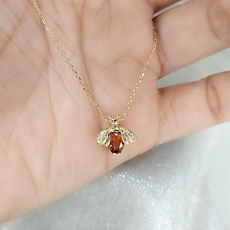 Honey Bee Citrine Diamond Necklace This beautiful necklace is perfect for any animal lover. The honey bee necklace features a cute little bee pendant made of yellow gold with an oval-shaped citrine. The necklace is also said to bring luck to the wearer, making it a great gift for anyone. [Made to Order] * Metal: 925 Sterling Silver Choice of Gold Color: Sterling Silver, 18K Rose Gold Vermeil, 18K Yellow Gold Vermeil Main Stone: Natural Citrine, Oval Shape, 6x4 mm, 1 pc Side Stone: Cubic Zirconia Handmade Honey Color Jewelry Gift, Handmade Honey-colored Jewelry For Gifts, Handmade Honey Jewelry For Gift, Lucky Necklace, Orange Citrine, Gem Pendant, Necklace For Her, Bee Pendant, Bee Necklace