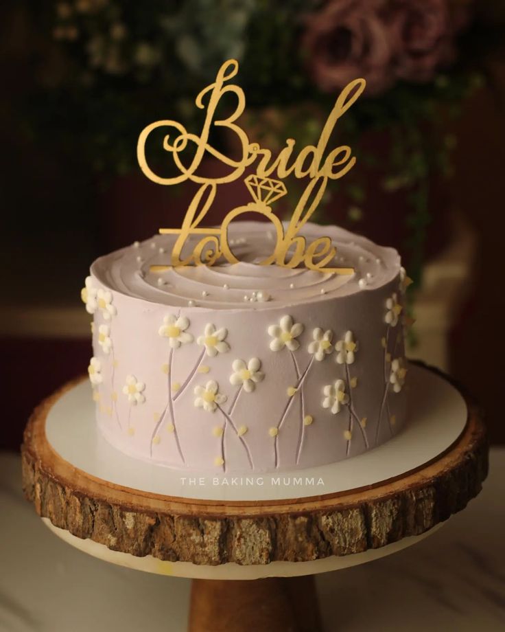 the cake is decorated with flowers and gold lettering