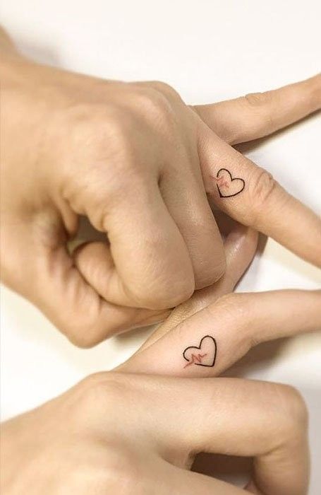 two hands with heart tattoos on their fingers