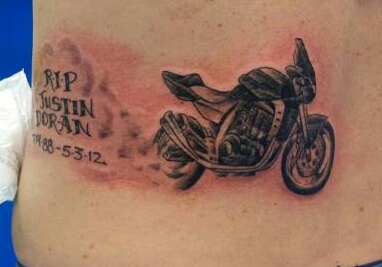 a tattoo on the back of a woman's stomach that has a motorcycle design