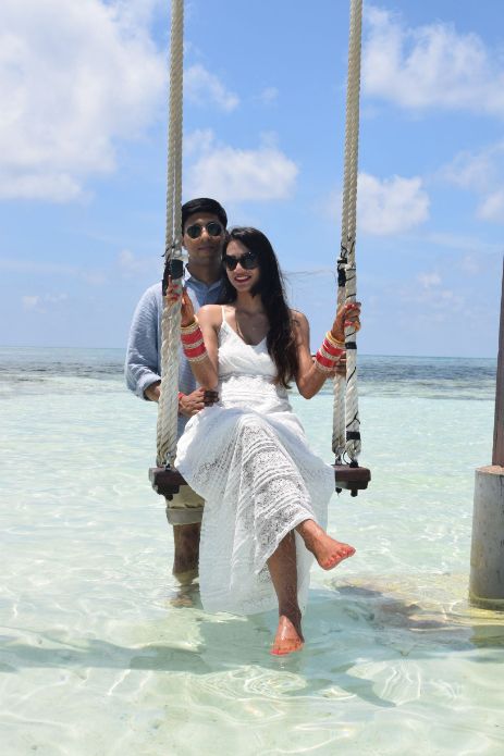 a man and woman sitting on swings in the water