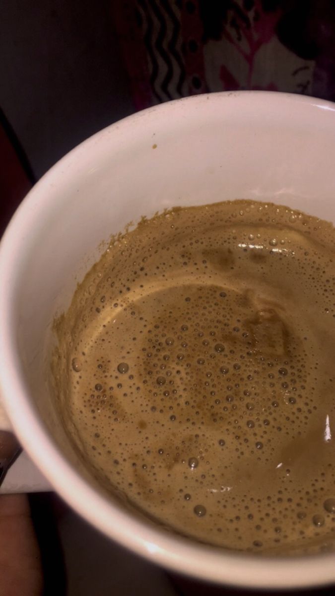 a white bowl filled with brown liquid on top of a table