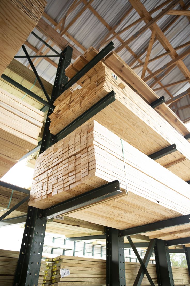 several stacks of wood stacked on top of each other in a room with metal beams