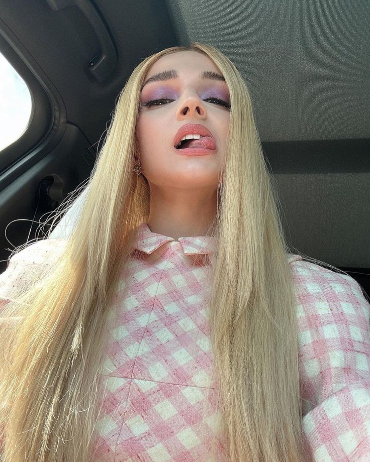 a woman with long blonde hair wearing pink and white checkered shirt