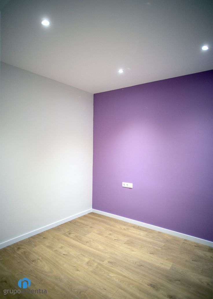 an empty room with purple walls and wooden floors