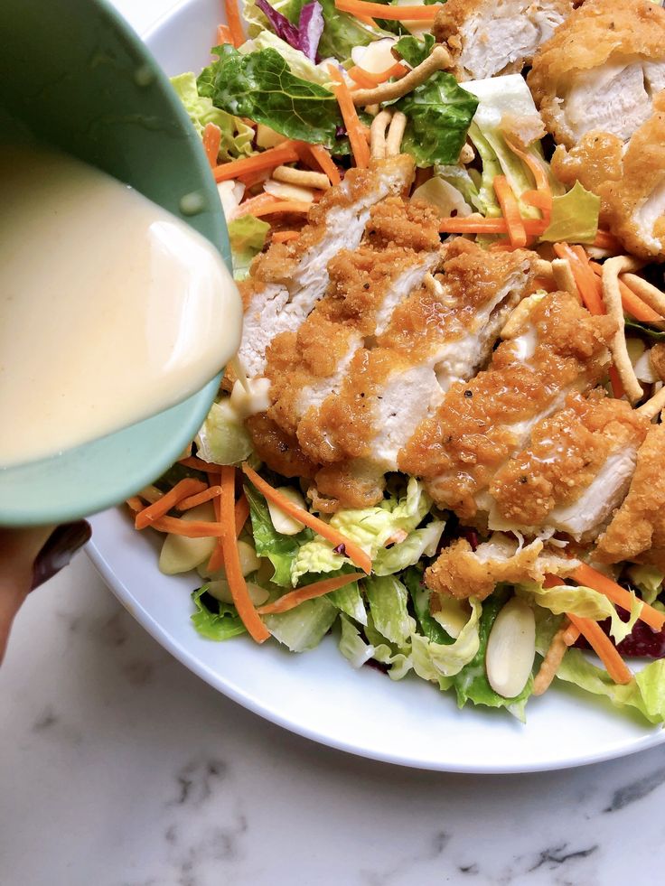 a salad with dressing being poured onto it