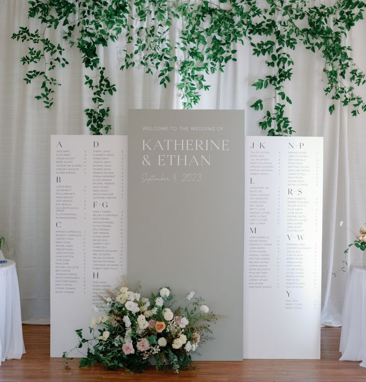 a table with flowers and greenery on it next to a seating chart for a wedding