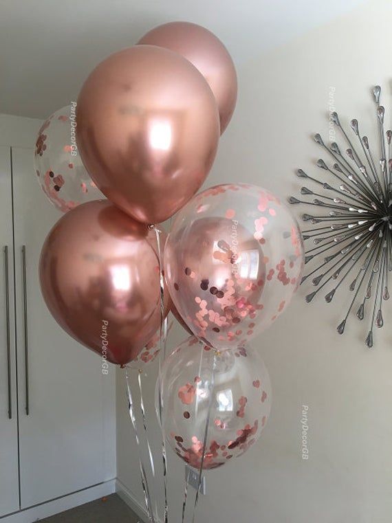 some pink and gold balloons are hanging on the wall