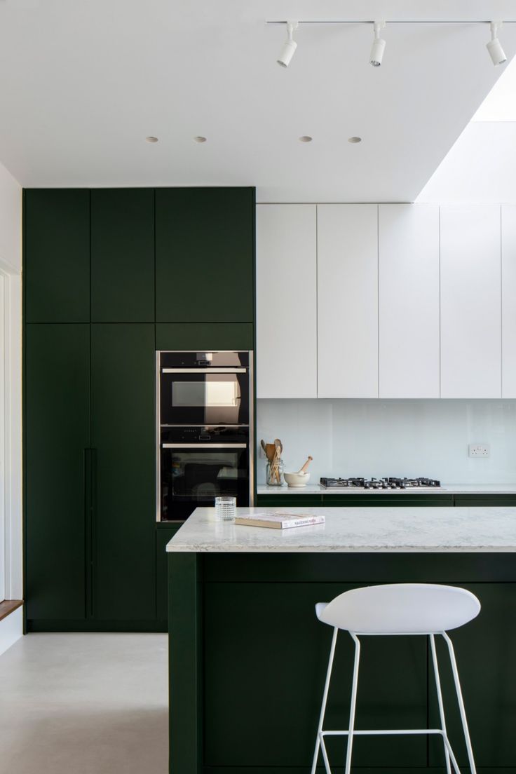 a kitchen with green cabinets and white stools in front of an island countertop