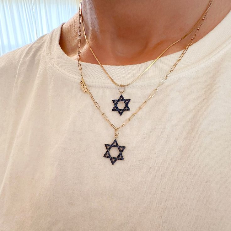 This meaningful pendant is the universal symbol of the Jewish star, known as the Star of David.  The charm is composed of 14K solid gold and beautifully finished with AAA quality natural real round brilliant cut blue sapphires which are accented with black rhodium detailing.   ♦ Star of David Dimensions: approximately 12.5mm (W) x 12.5mm (L) not including the bail x 1.75mm thickness ♦ Weight: approximately 1.25 grams of 14K solid gold ♦ Metal Finish: High Shine Polish ♦ This design is available Gold Star Of David Jewelry For Hanukkah, Yellow Gold Star Of David Charms Jewelry, Symbolic 14k Gold Star Of David Jewelry, 14k Gold Celestial Star Of David Jewelry, Yellow Gold Charm Necklace With Star Of David Charm, Symbolic Yellow Gold Star Of David Jewelry, 14k Gold Star Of David Necklace, Tarnish Resistant, 14k Gold Star Of David Necklace Engraved, Yellow Gold Star Of David Necklace