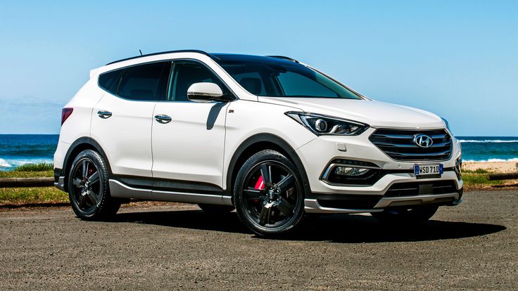 the front end of a white suv parked by the ocean