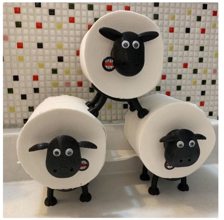 three black and white sheep sitting on top of each other in front of a tiled wall