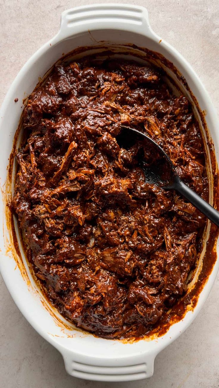 a white bowl filled with chili sauce and topped with a black spoon on the side