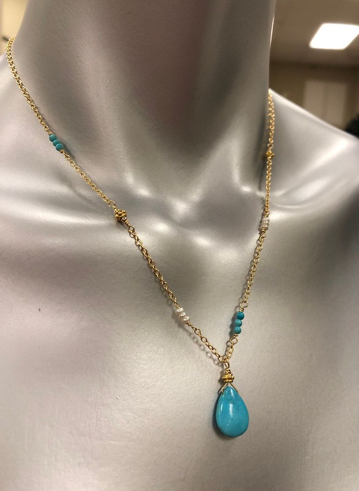 This beautiful necklace is designed with a 10mm X 15mm smooth nugget of Sleeping Beauty Turquoise (that beautiful bright blue color) and wired into a pendant with a Vermeil Bali gold bead. The pendant dangles from sparkly cable chain. Sections of the necklace are accented with tiny (2mm) smooth, round turquoise, Vermeil Bali beads that match the pendant, and tiny (2mm) white freshwater pearls for a unique one of a kind design.The look of Turquoise with gold is a beautiful change to the tradition Turquoise Drop Necklace For Jewelry Making, Turquoise Dangle Necklaces With Gemstone Beads, Turquoise Teardrop Jewelry With Beaded Chain, Elegant Turquoise Teardrop Beaded Necklaces, Elegant Turquoise Wire Wrapped Beaded Necklace, Elegant Handmade Teardrop Turquoise Necklace, Gold Jewelry With Gemstone Beads Teardrop Pendant, Elegant Handmade Turquoise Teardrop Necklace, Elegant Gold Single Strand Turquoise Necklace