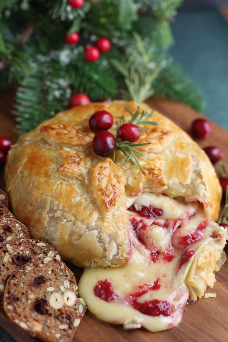 a pastry with cheese and cranberry sauce on it sitting next to some bread