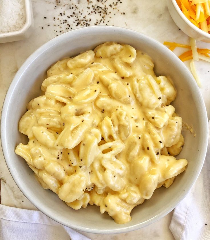 a white bowl filled with macaroni and cheese on top of a marble counter