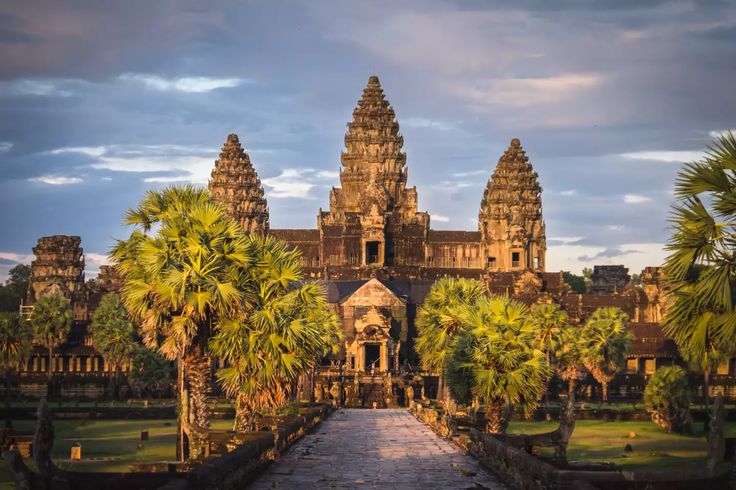 an ancient building with palm trees in the foreground