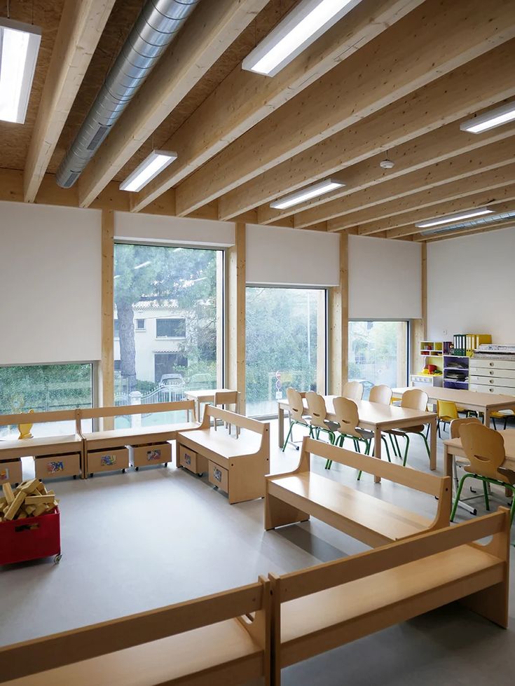 an empty classroom with wooden benches and desks