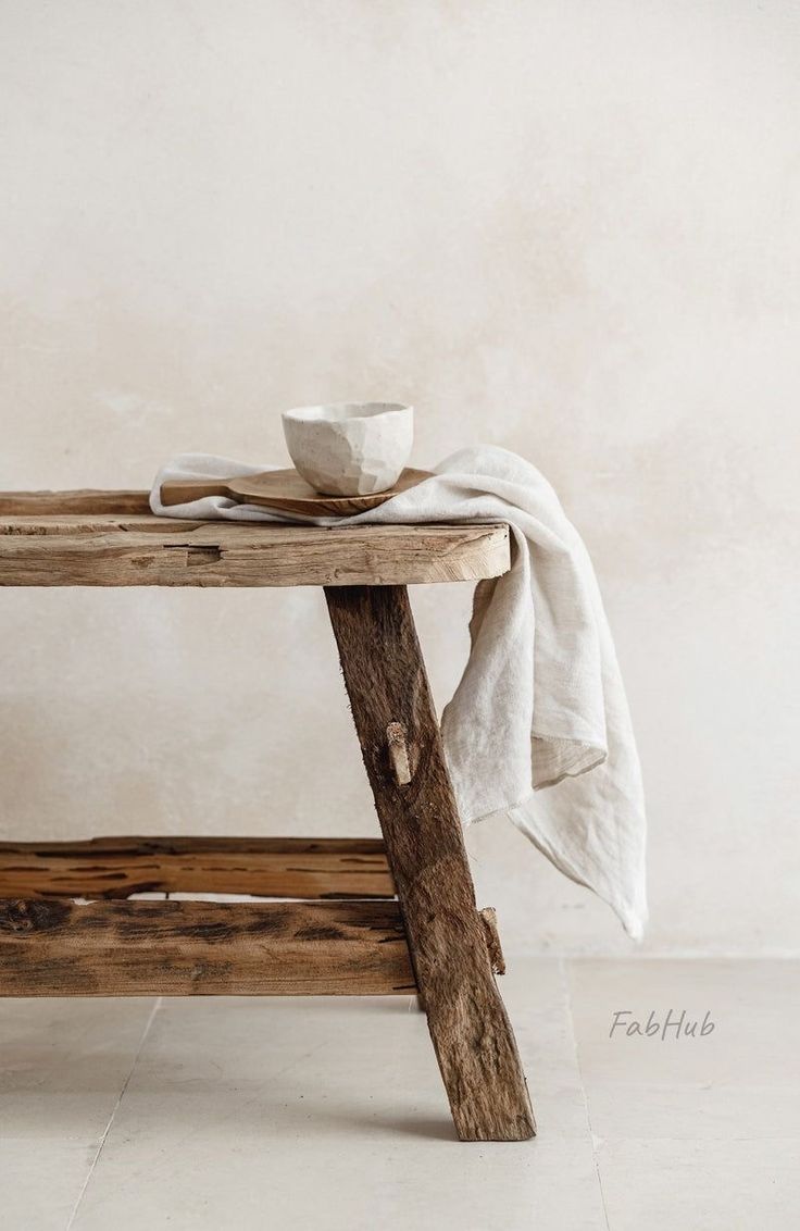 a wooden table with a bowl on it and a white cloth draped over the top