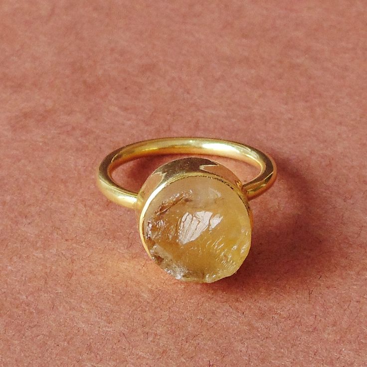 For every November born who desire the gift of protection and strength, this natural citrine ring is a design which proves to be a dream come true. The birthstone comes in a delicate stackable design which leaves no room for any fashion compromise for the wearer making this an ideal gift choice.  Elegant 18K Yellow Gold Plated Natural Raw Citrine Brass Stone Ring, Round Stone Stacking Ring, Unique Birthstone Ring For Women Product Details Item Code: BJBR-1743 Stone Name: Citrine Stone Size: 10 mm Metal: 18K Yellow Gold Plated Over Brass Ring Sizes: Please choose from drop down menu. If you do not see your finger size, select custom and I'll make a ring just for you!  Note:- These rings you will receive may vary slightly in color from the images because these are natural gemstones and vary Citrine Birthstone Crystal Ring Fine Jewelry, Fine Jewelry Citrine Crystal Ring With Birthstone, Yellow Gemstone Open Ring Jewelry, Oval Citrine Ring With Spiritual Style, Spiritual Oval Citrine Ring, Citrine Gemstone Crystal Promise Ring, Yellow Citrine Birthstone Ring, Yellow Gold Citrine Birthstone Crystal Ring, Citrine Crystal Promise Ring With Gemstone