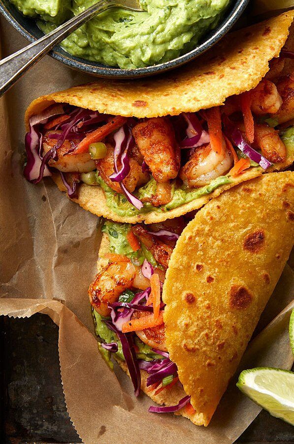 two tacos with shrimp and guacamole on the side