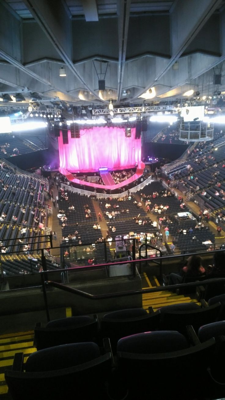 an empty stadium filled with people sitting on the bleachers and looking at the stage