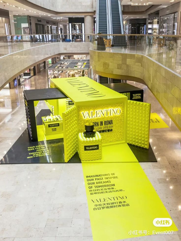 a yellow bench in the middle of a mall with advertisements on it's sides