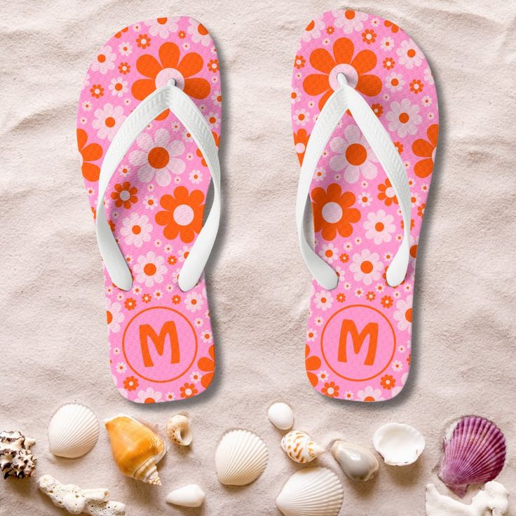 a pair of flip flops sitting on top of a sandy beach next to shells