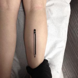 a person with a tattoo on their arm and leg, holding a pen in the other hand