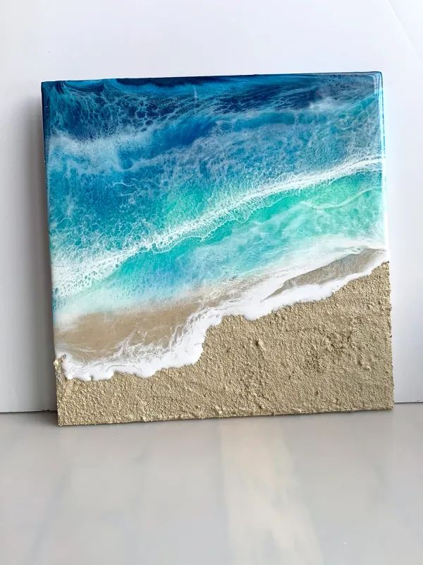 an ocean scene painted on the side of a wall with white sand and blue water