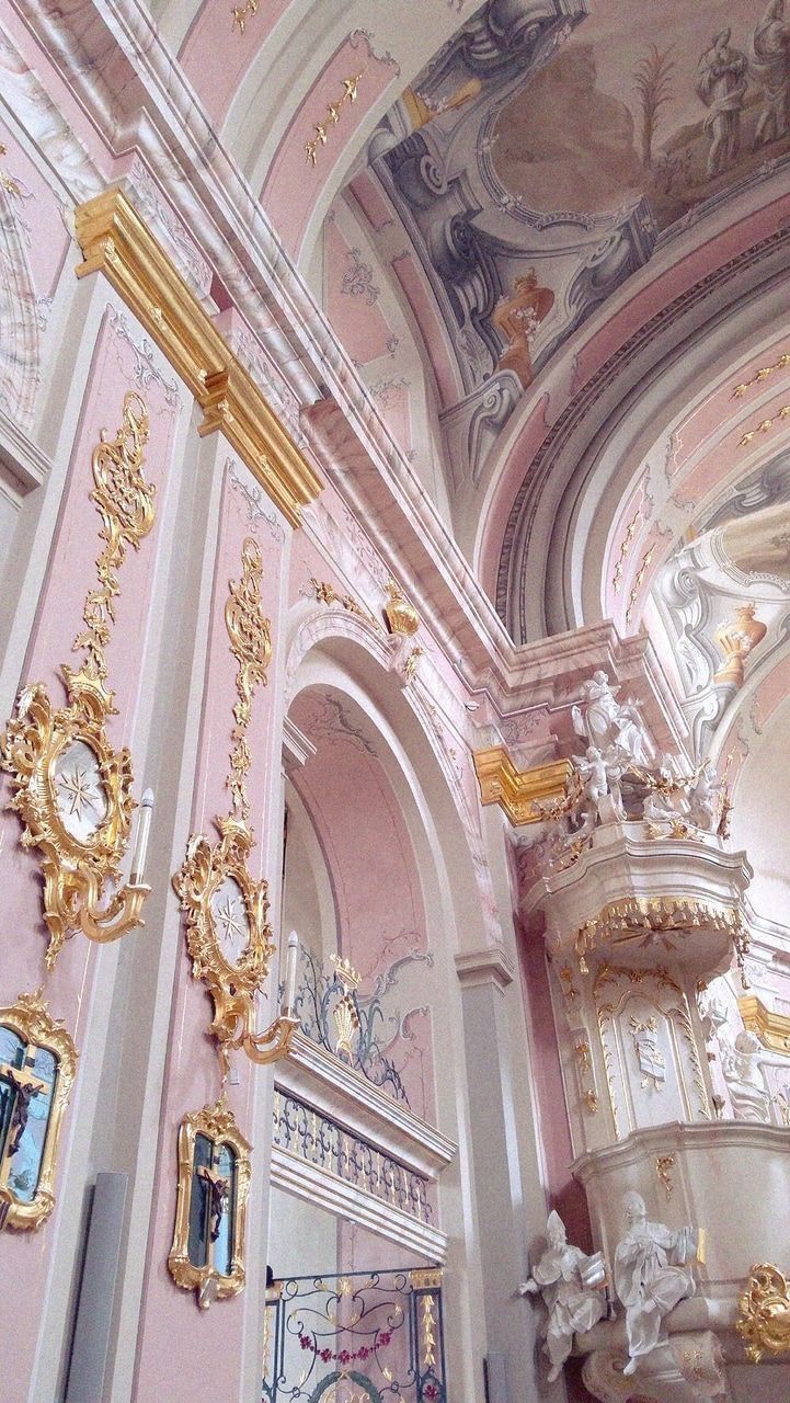 an ornately decorated room with gold and white decorations on the ceiling, painted in pastel pink