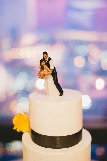 a bride and groom figurine sitting on top of a white tiered cake