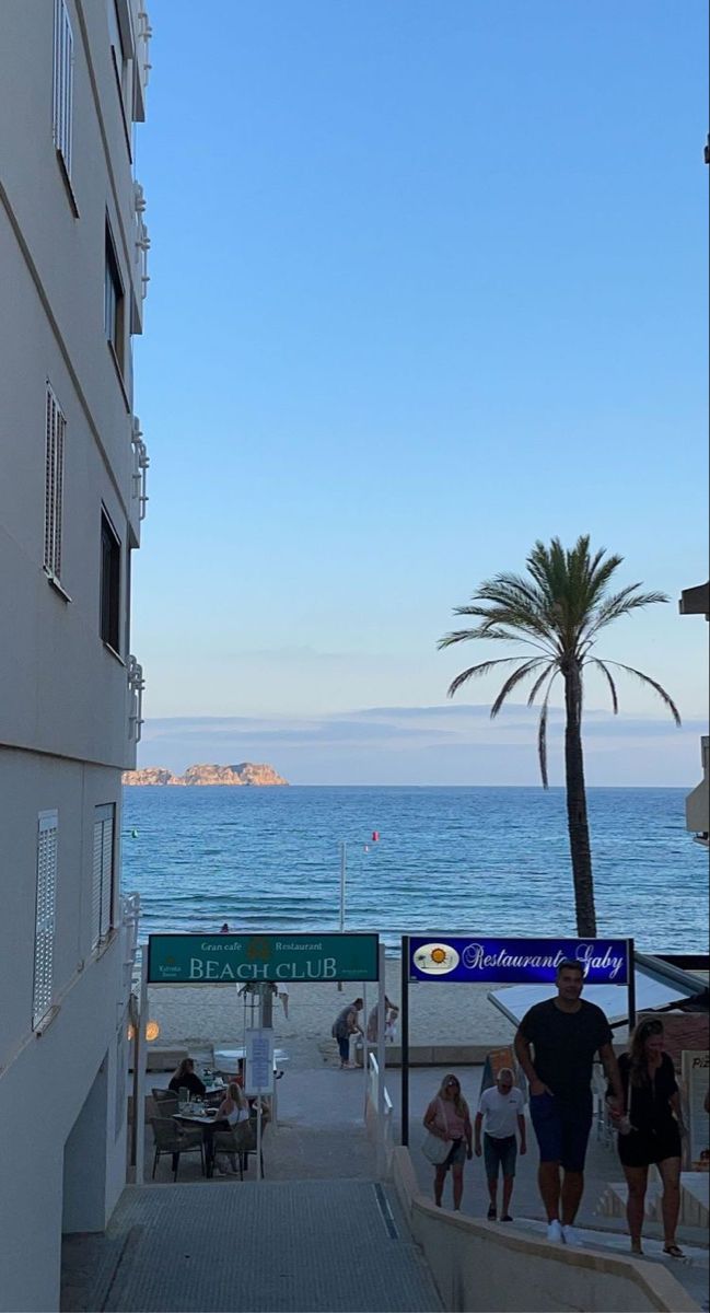 people are walking up and down the stairs to the beach in front of an apartment building