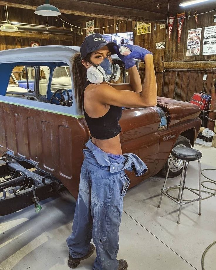 a woman is working on an old car in a garage with her hands on the hood