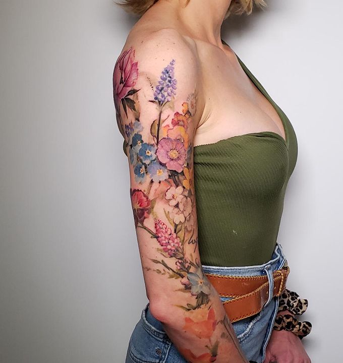 a woman with a tattoo on her arm holding a cell phone in her right hand