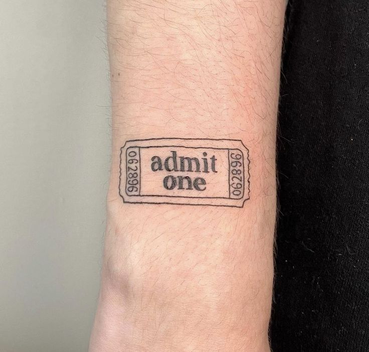 a person's arm with a ticket tattoo on it that says admit one in black ink