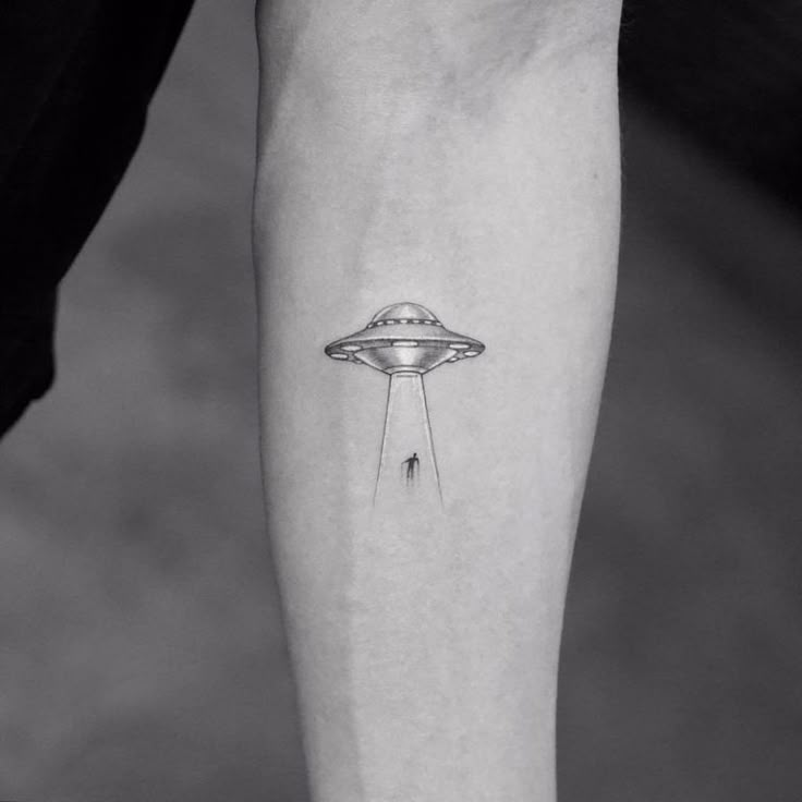 a black and white photo of a person's arm with an alien tattoo on it